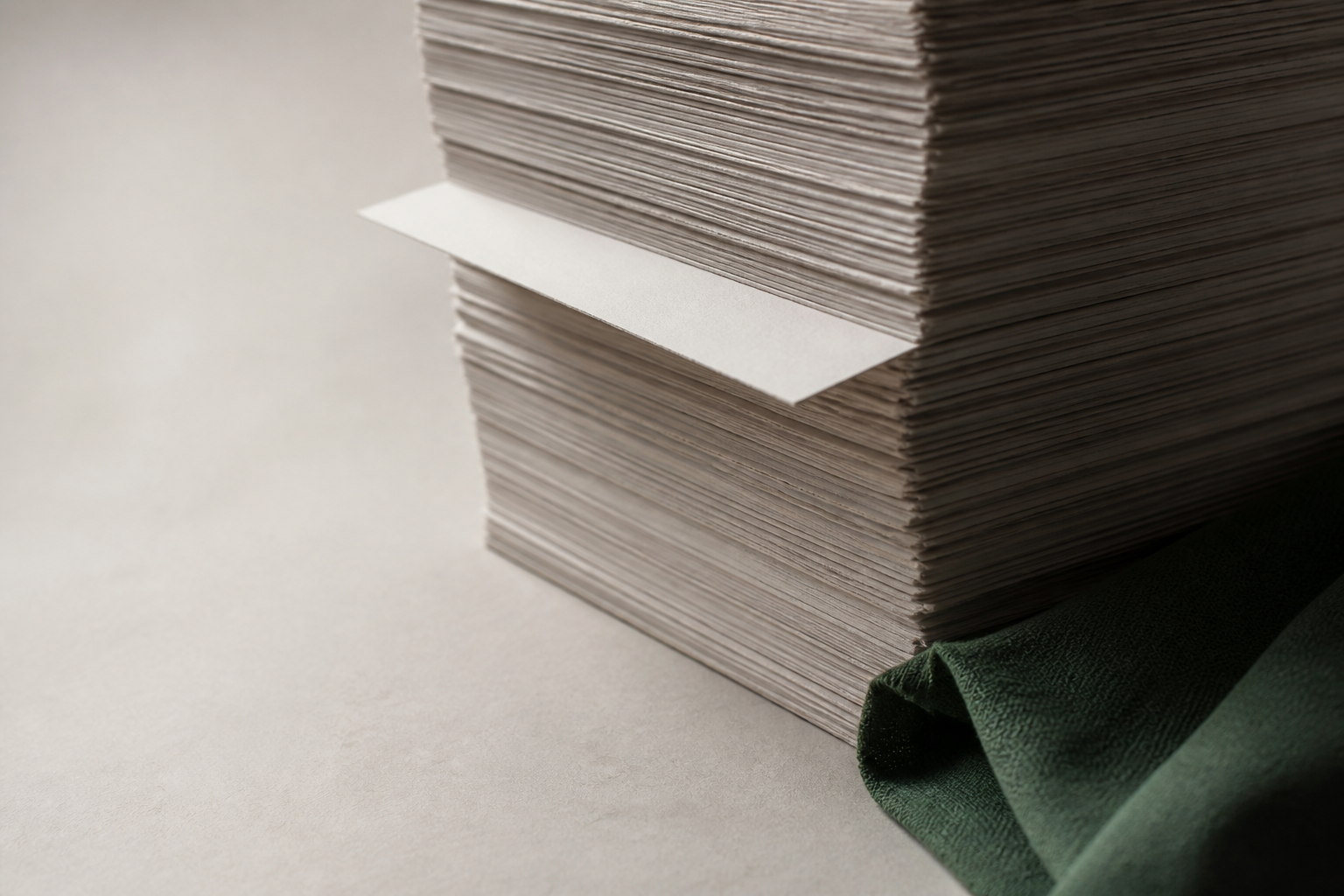 A tall stack of unbound paper sheets, one sheet pulled slightly forward into the light